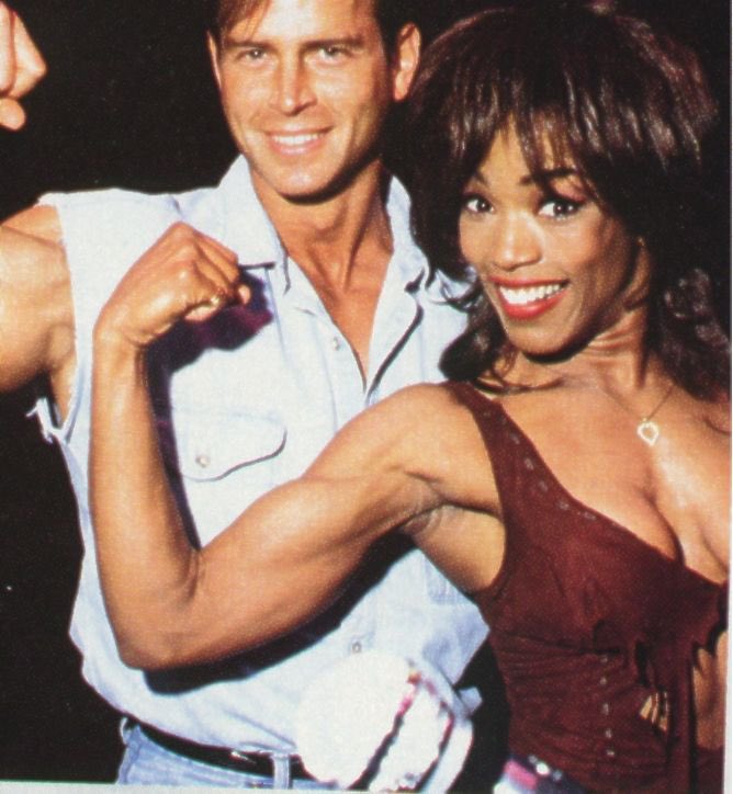 Angela and her trainer flexing their muscles